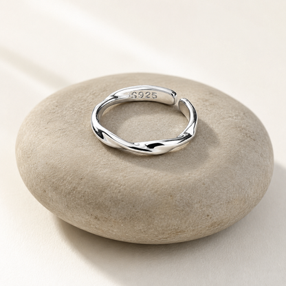 Sterling silver twisted adjustable ring resting on a smooth stone in soft natural light