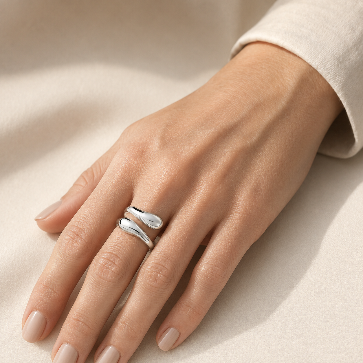 Sterling silver water drop ring worn on a woman's finger, showing the open adjustable bypass design